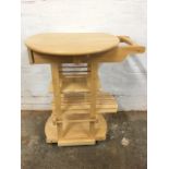 A beech kitchen trolley, the circular top with two drop flaps above a drawer, having wine rack,