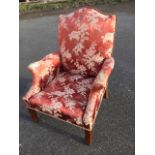 A Georgian style upholstered armchair with arched padded back above scrolled arms and sprung