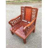 A Chinese hardwood armchair with central panel to back framed by pierced scroll carved sides, the