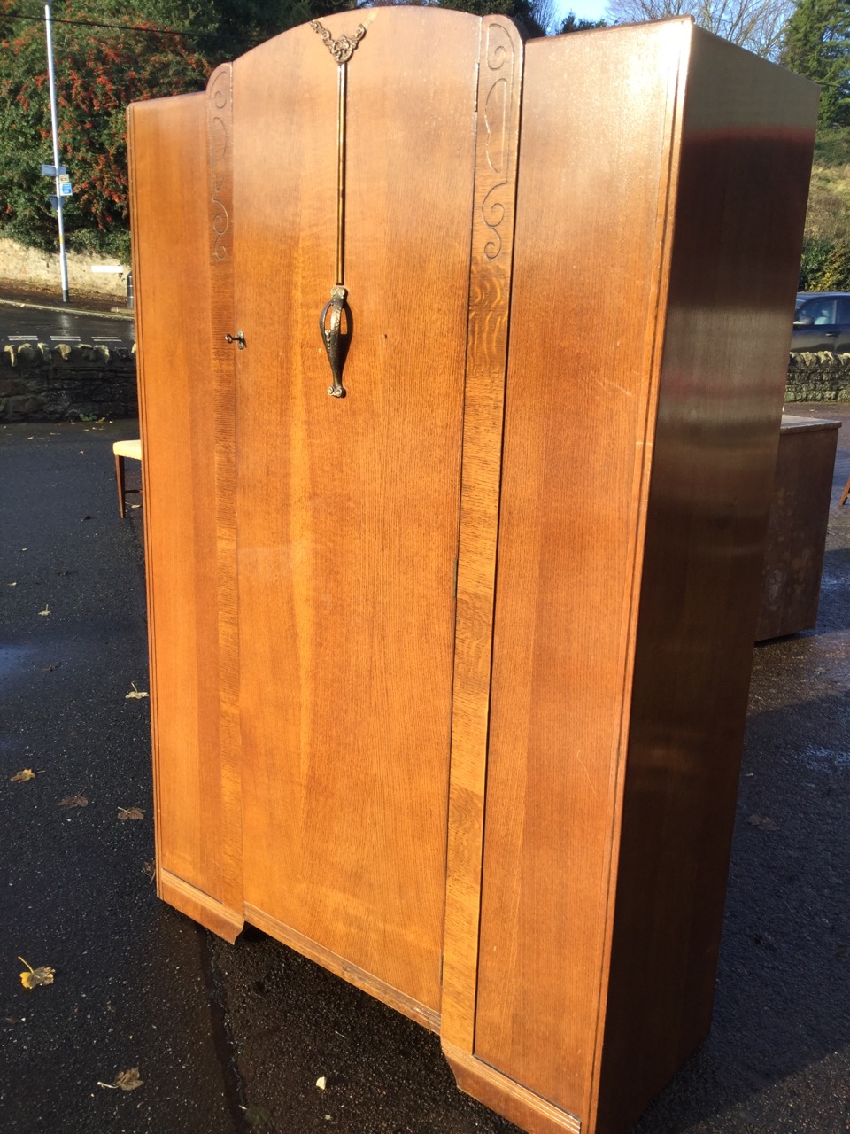 An oak wardrobe by Lawrencia, having arched door with press moulded floral decoration mounted with