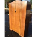 An oak wardrobe by Lawrencia, having arched door with press moulded floral decoration mounted with