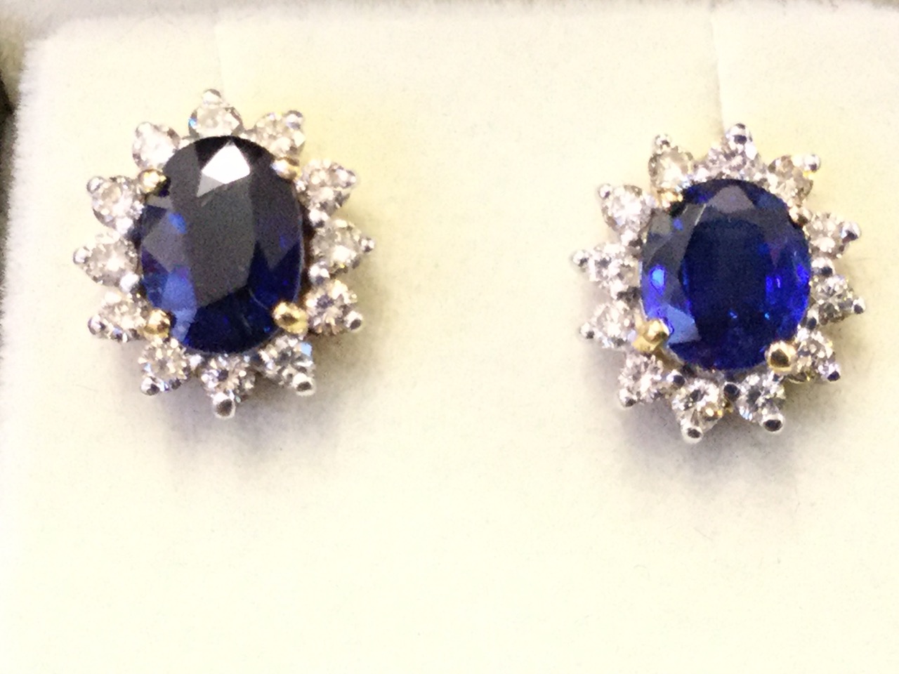 A pair of 18ct gold sapphire & diamond earrings, the oval claw set sapphires weighing just under