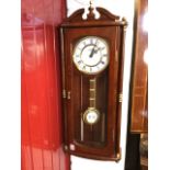 A Vienna style mahogany wallclock, the pediment with brass finial above a glazed door enclosing