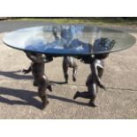 A contemporary bronze coffee table with circular plate glass top supported by three gambolling putti