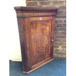 A nineteenth century oak corner cabinet with moulded dentil cornice above a mahogany frieze, the