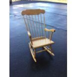 A spindleback rocking chair with splayed arms above a plain seat, raised on ring-turned legs with