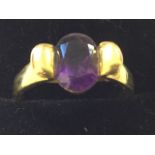 An 18ct gold amethyst ring, the tapering shoulders with shaped wings framing an oval bezel set cut