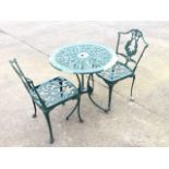 A circular metal garden table with a pair of chairs, the tabletop with pierced scrolled