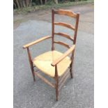 An arts & crafts oak ladderback armchair, with rounded platform arms on tapering supports, the