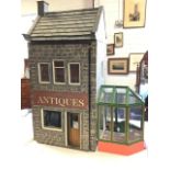 A large childs doll house modelled as an antique shop with attached glazed conservatory, having wood