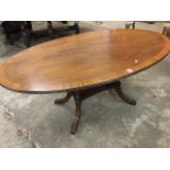 An oval mahogany crossbanded coffee table, the top with ribbed edge supported on four turned columns