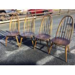 A set of four elm Ercol dining chairs, having hooped backs on spindles above rounded solid seats,