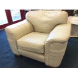 A large contemporary ivory coloured leather armchair with padded back and arms above a loose cushion