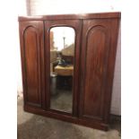 A Victorian mahogany three-door combination wardrobe, with plain rounded cornice above central