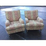 A pair of contemporary upholstered armchairs with loose cushions and long sprung seats, raised on