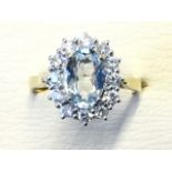 An 18ct gold aquamarine & diamond cluster ring, the oval claw set aquamarine weighing over a