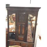 A late Victorian stained walnut wardrobe decorated with scrolled carvings having bevelled mirror