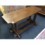 An arts & crafts style oak table, the cut-corner top on twin rectangular supports and pegged