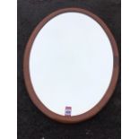An oval mahogany wall mirror in cushion moulded frame with bevelled plate. (19in x 26in)
