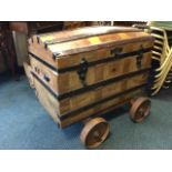 A domed top leather covered seamans chest with wood slats, mounted on later trolley base with cast