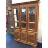 A contemporary hardwood dresser with moulded cornice above scroll carved glazed doors enclosing