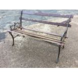 A 4ft garden bench with scrolled cast iron ends raised on channelled sabre legs, the slats
