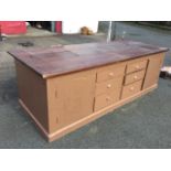 A large painted double-sided shop counter, with cleated three-board pitch pine top above cupboards