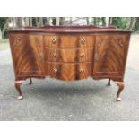 A serpentine fronted mahogany sideboard with scroll carved back, having three central drawers