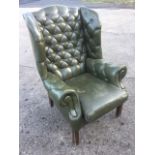 A button upholstered Georgian style oak wing armchair with arched back and scroll shaped arms