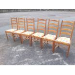 A set of six pine ladderback chairs, the slatted seats with cushions, raised on turned legs &