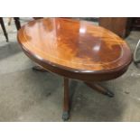 An oval mahogany flame coffee table, the moulded top inlaid with white line supported on a