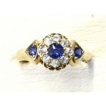 An 18ct gold sapphire & diamond ring, having circular panel claw set with central sapphire framed by
