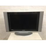 A Samsung DNle SRS flatscreen TV with integral speakers raised on oval stand. (33in x 8in x 21in)