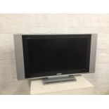 A Bush LCD2 flatscreen TV with integral speakers, raised on rectangular stand. (38in x 5in x 23in)