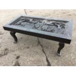A rectangular ebonised carved coffee table, the panel carved in relief with dancing figures and