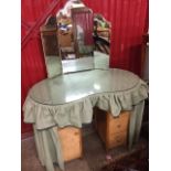 A fabric covered kidney shaped dressing table, the arched bevelled mirror with hinged wings above