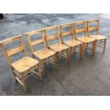 A set of six elm seated church chairs, the backs with praying rails above hymn book compartments,