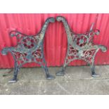 A pair of cast iron bench ends with circular roundels beneath scrolled arms, the pierced foliate