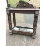 A Victorian carved oak stickstand, the back with lionmask and leaf scrolls above a chisel carved