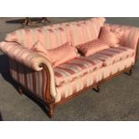 A reproduction Victorian style mahogany sofa with loose cushions having scroll carved arms and