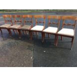 A set of six regency mahogany dining chairs with plain backs above scroll carved joining rails,