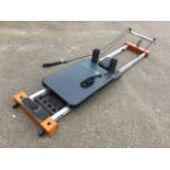 A Lineaflex exercise machine with sliding upholstered panel on rails, having two sprung cords,