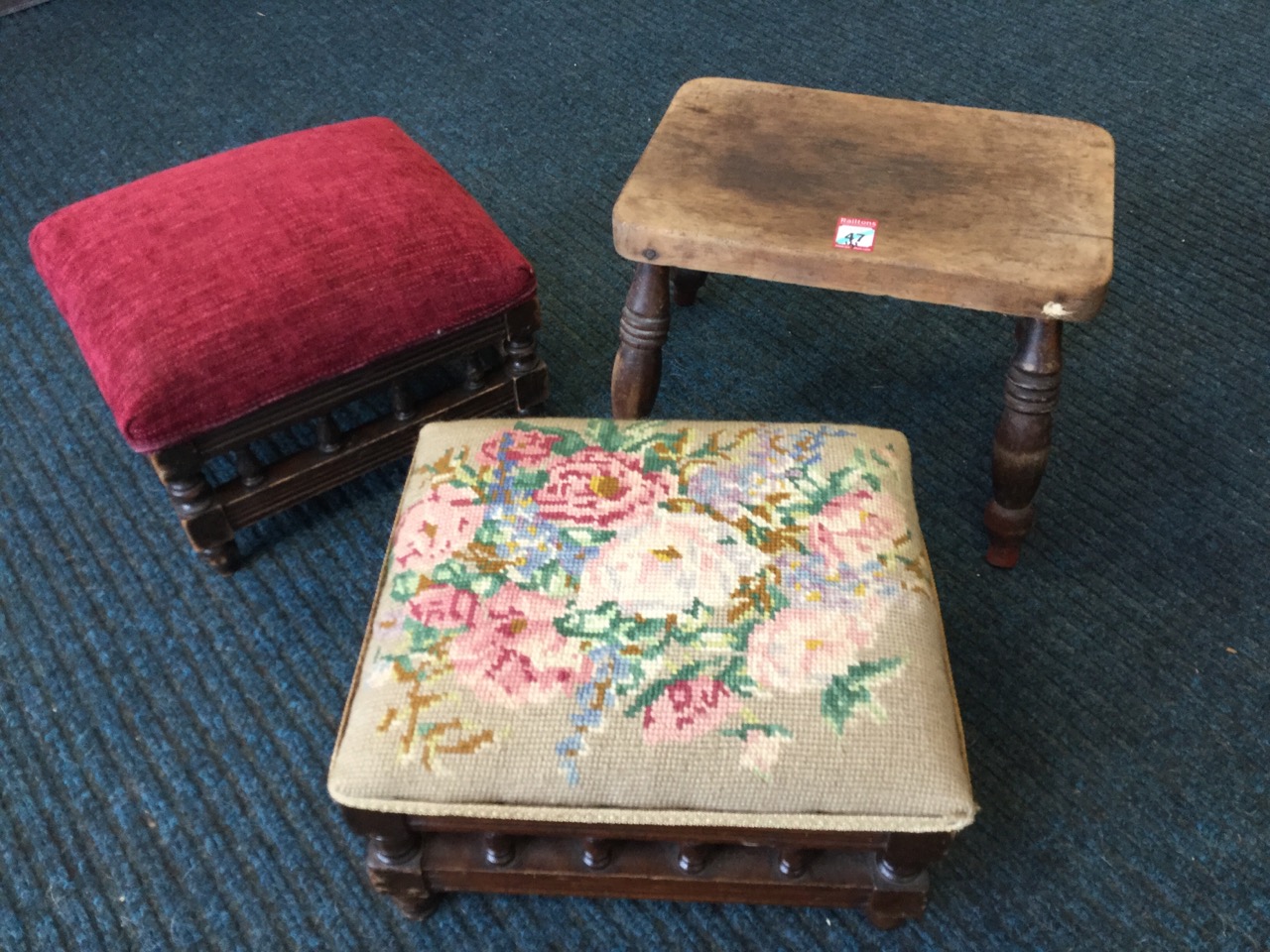 A near pair of upholstered footstools with turned gallery spindles in reeded rails, supported on