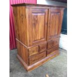 A hardwood cabinet with moulded cornice above fielded panelled doors supported on a chest with