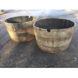 A near pair of large oak garden barrel tubs, the staves bound by metal strap bands. (28.5in x