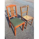 An Edwardian stained chair with carved back rail and tapering cane seat on turned legs; and a