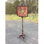 A Victorian rosewood firescreen, the rectangular moulded frame with scroll carved crest having