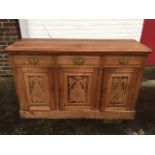 A late Victorian carved oak sideboard, the rectangular moulded top above three frieze drawers and