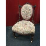 A Victorian mahogany nursing chair with oval upholstered back framed by angled fluted tapering