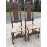 A pair of Carolean carved oak hall chairs, the backs with pierced scrolled crests above